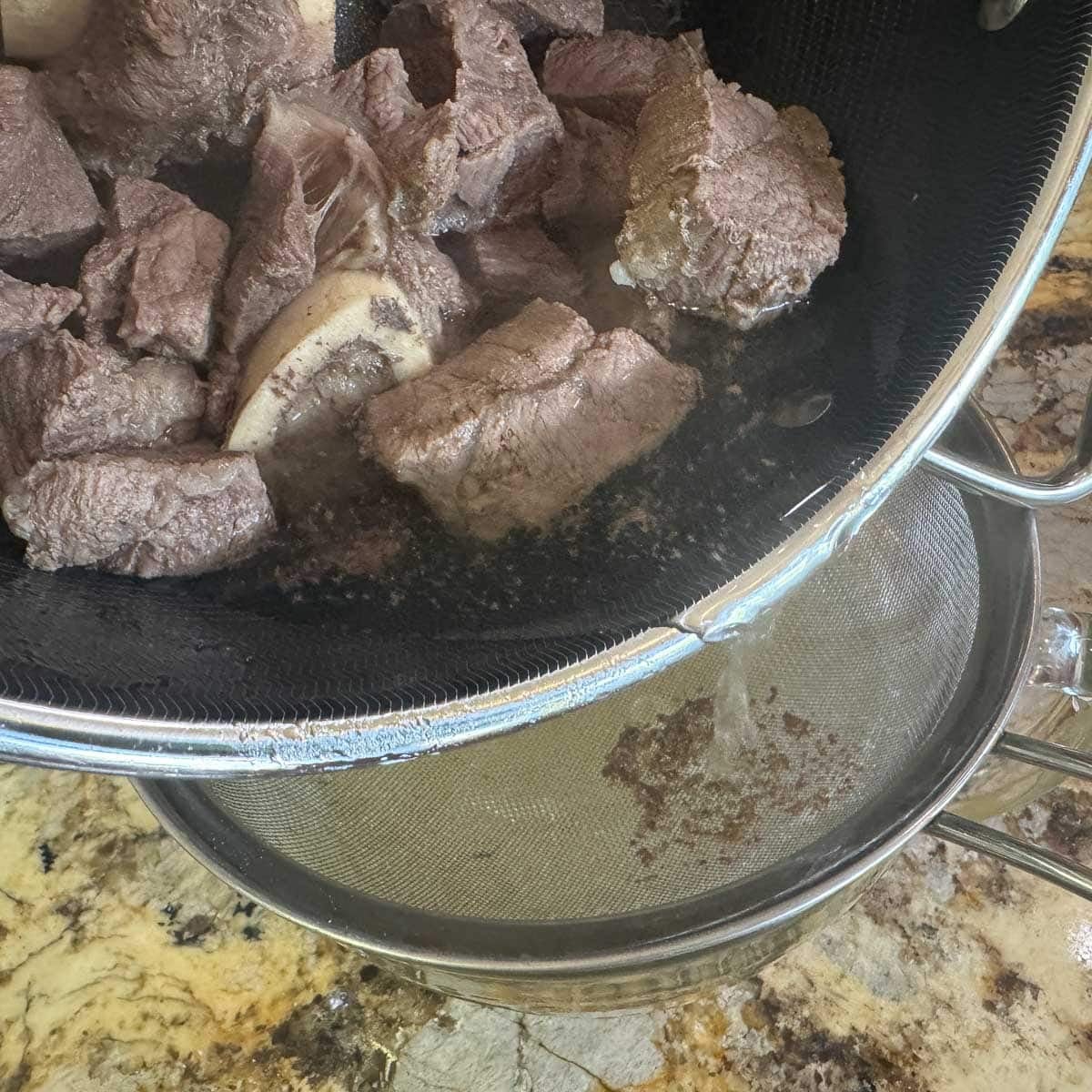straining beef broth through a strainer