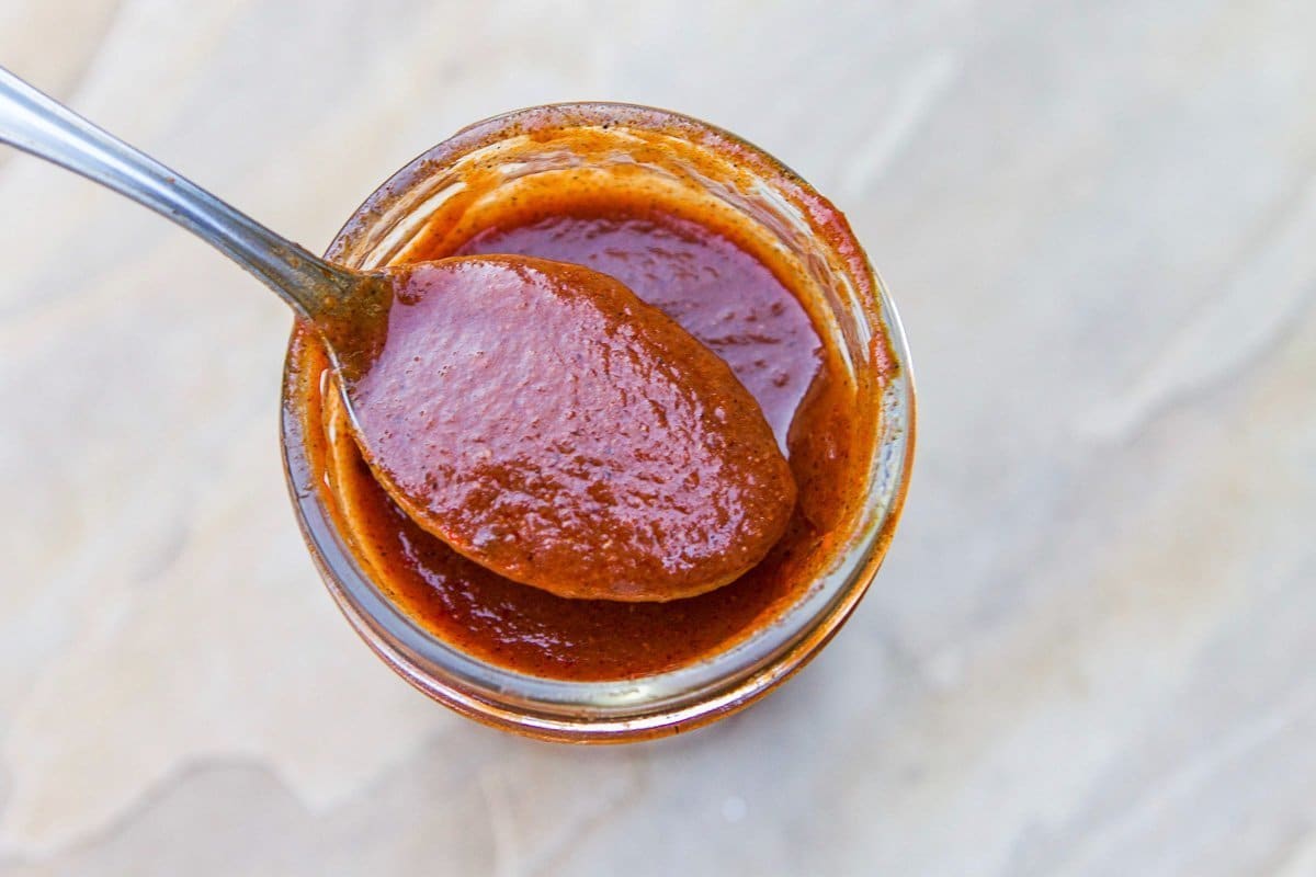 enchilada sauce in a spoon over a jar