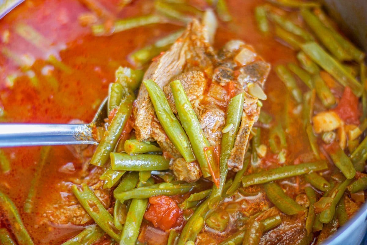 fasolia (bean stew) in a spoon over a pot