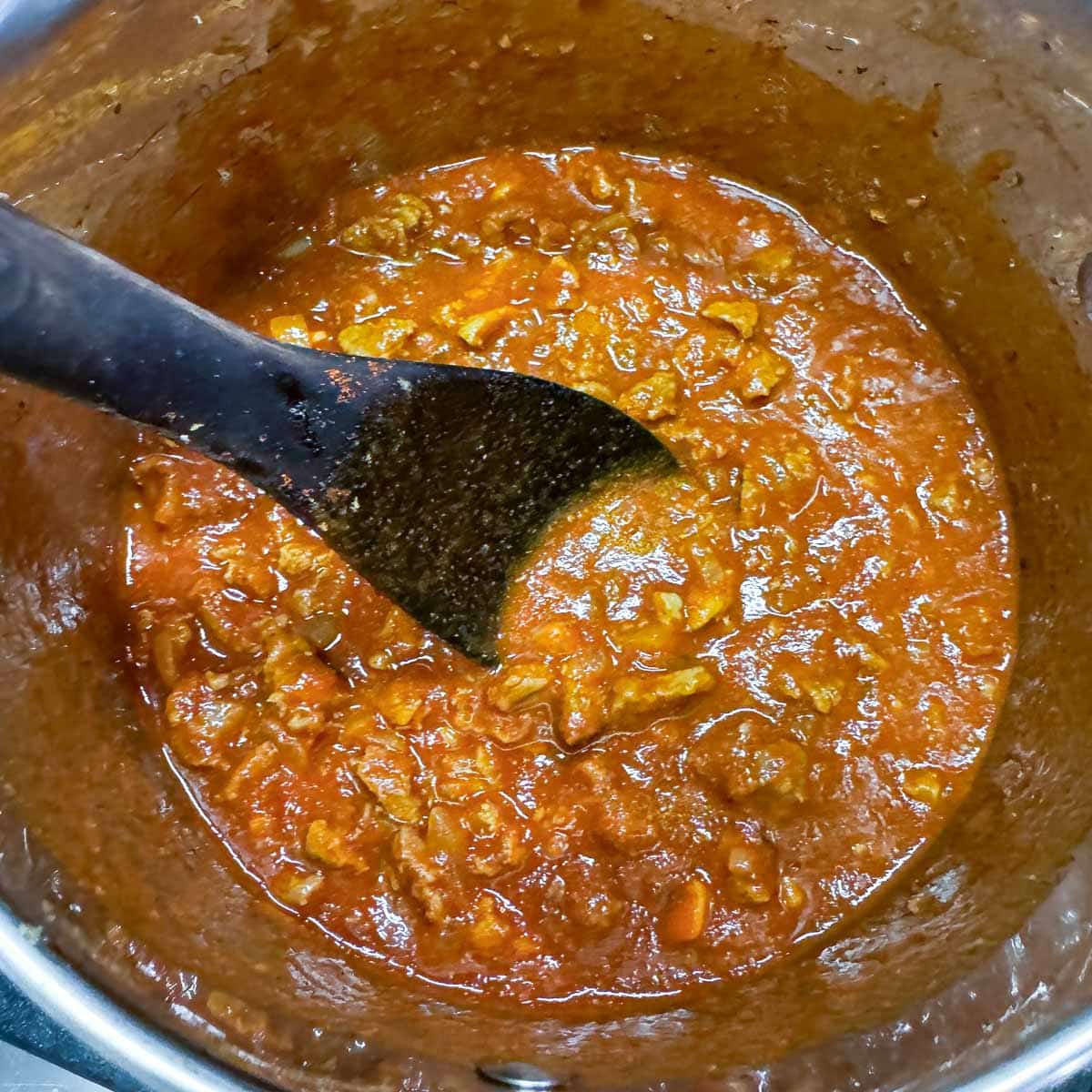 diced meat and sauce being stirred in a pot.