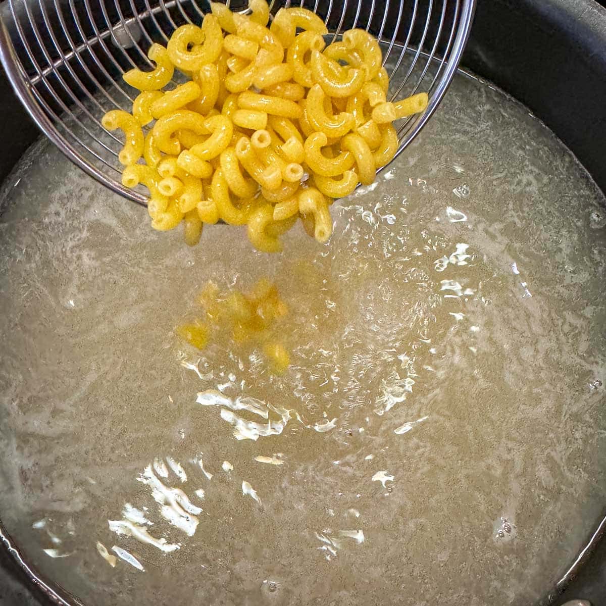 adding macaroni to boiling water.