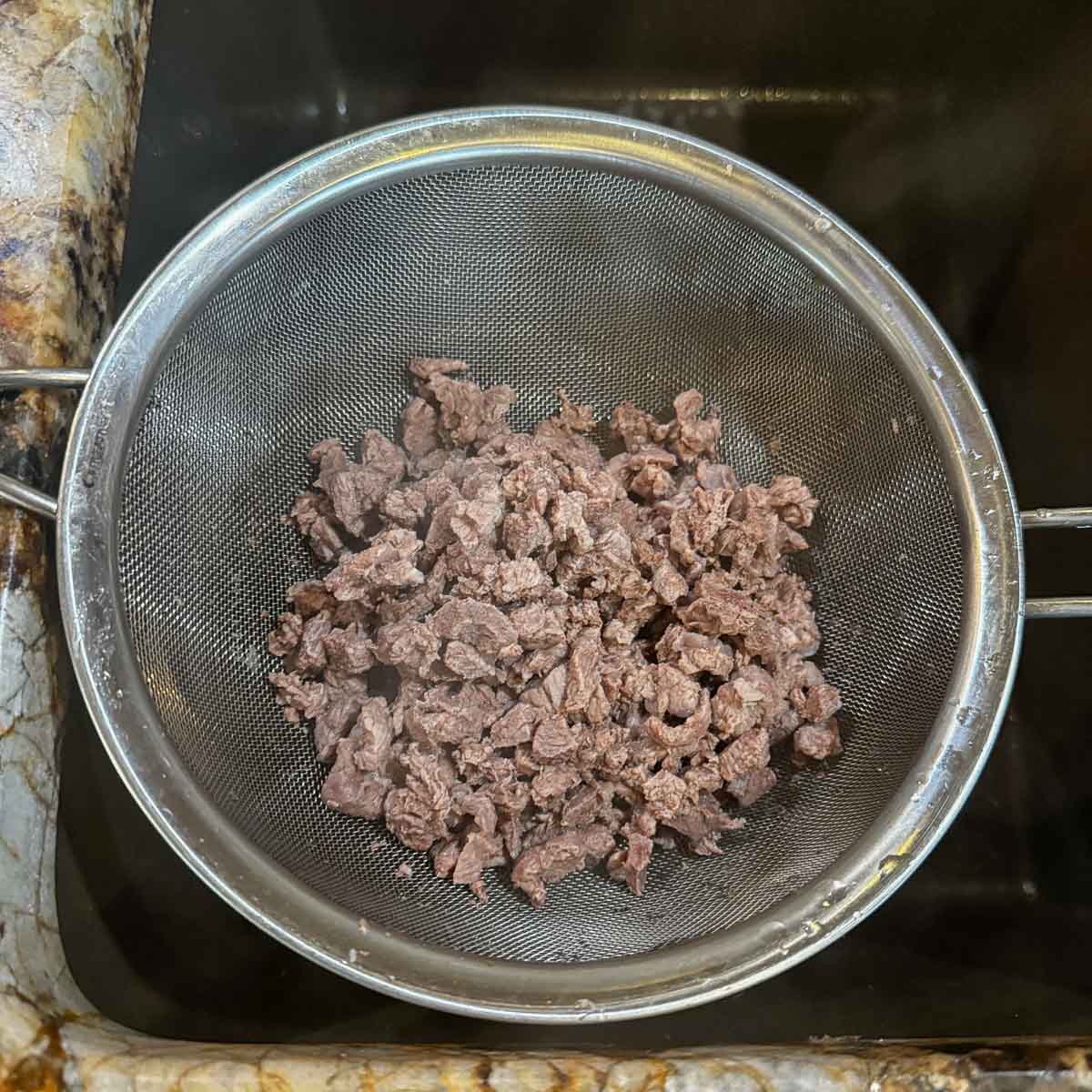 diced meat in a strainer.
