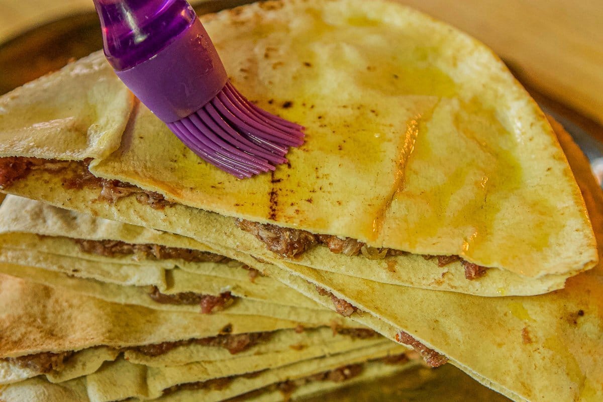 stuffed pita bread being brushed with oil