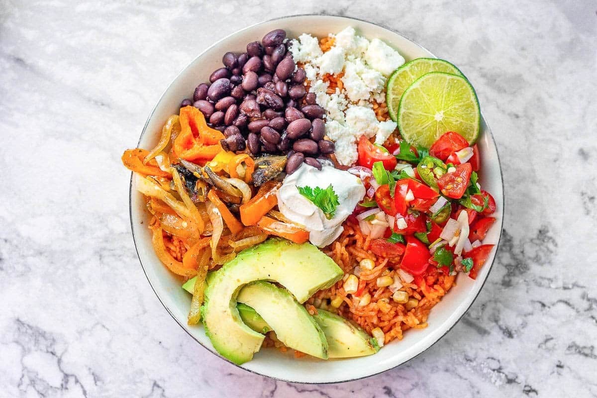 vegetarian Mexican rice bowl full of veggies, cheese, beans, etc.