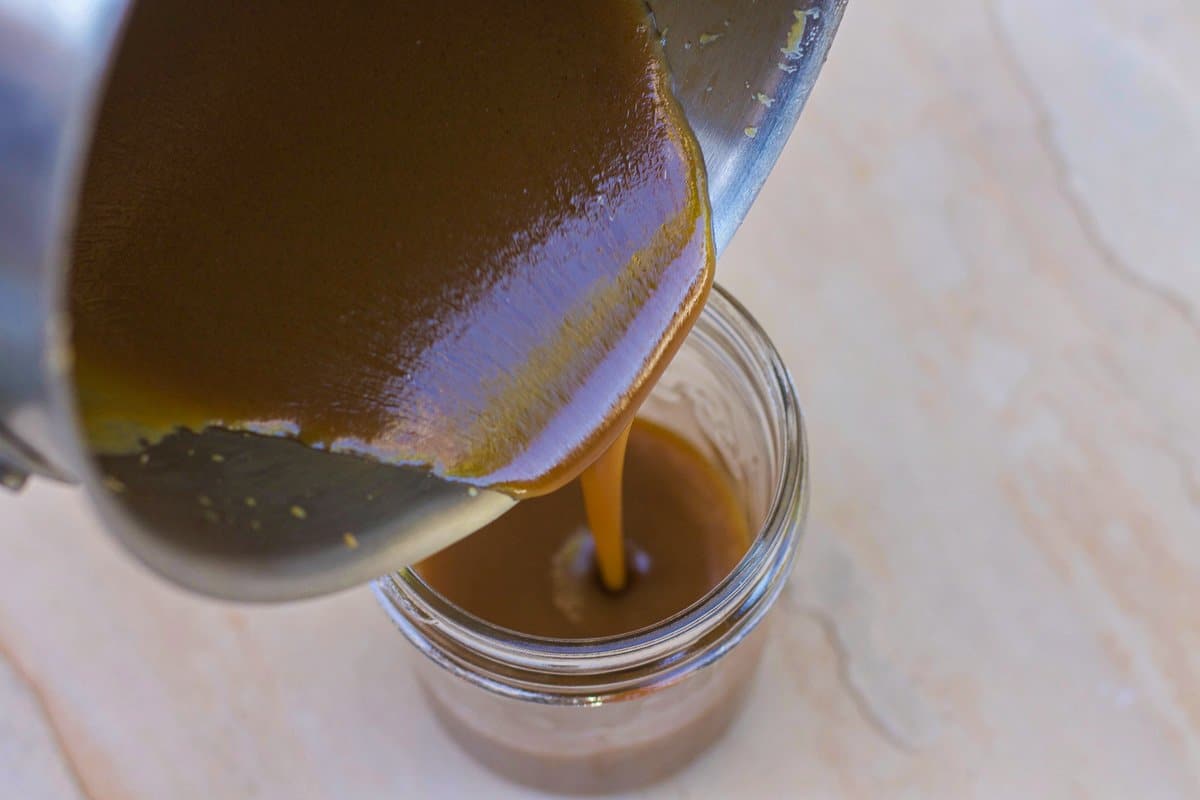 pouring caramel sauce in a jar