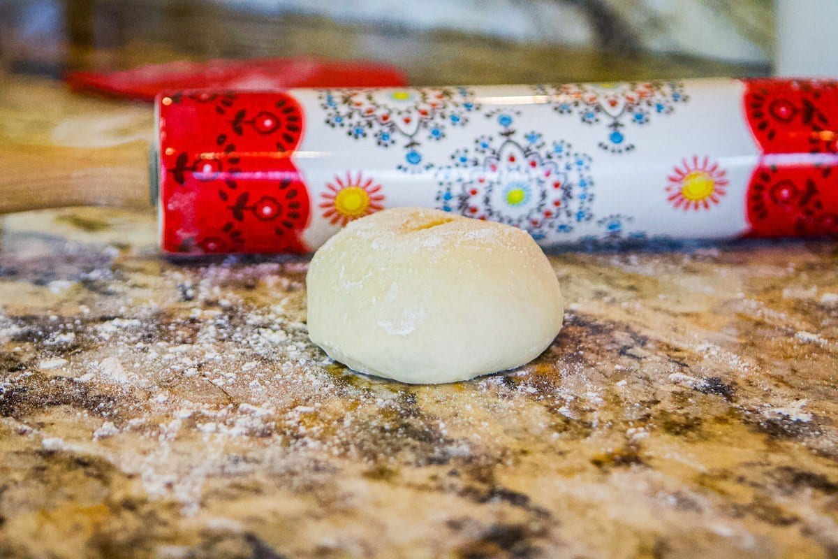 dough ball with a colorful rolling pin behind it