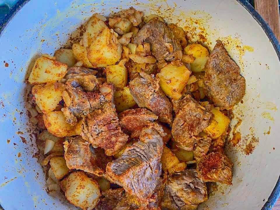 potatoes and cubed meat in a white pot