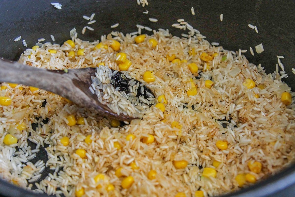 rice and corn being cooked in a pan