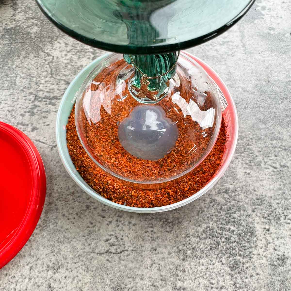 margarita glass being dipped into tajin seasoning.