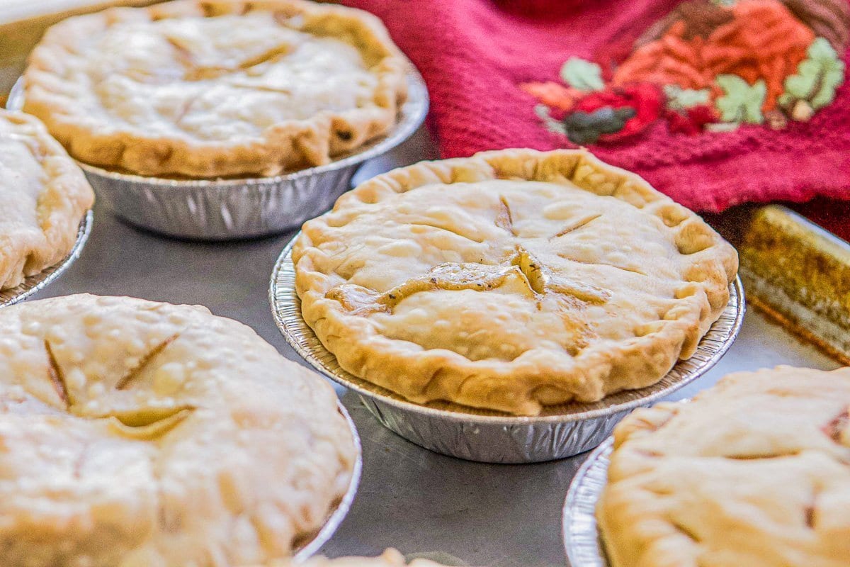 mini turkey pot pies on a cookie sheet with a red kitchen towel in the background 