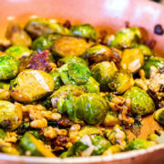 roasted brussel sprouts with bacon, cheese and pine nuts in a pan