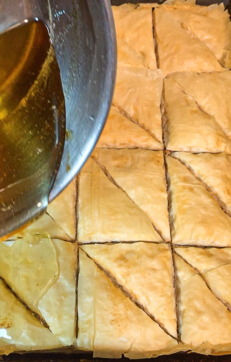 pouring syrup over baklawa