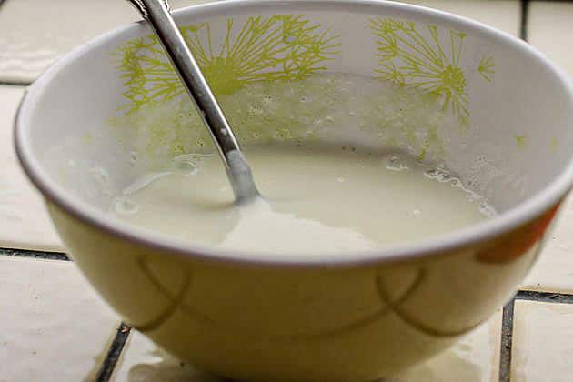 ½ full yogurt bowl with a spoon in it on a white tiled counter