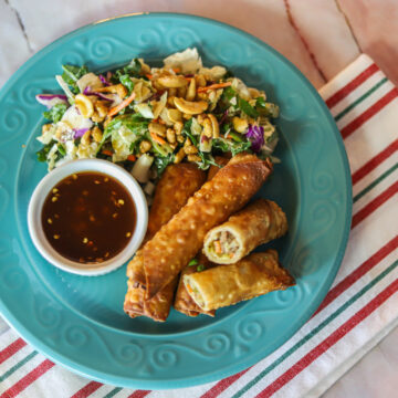 eggrolls, salad, and sauce for dipping on blue plate