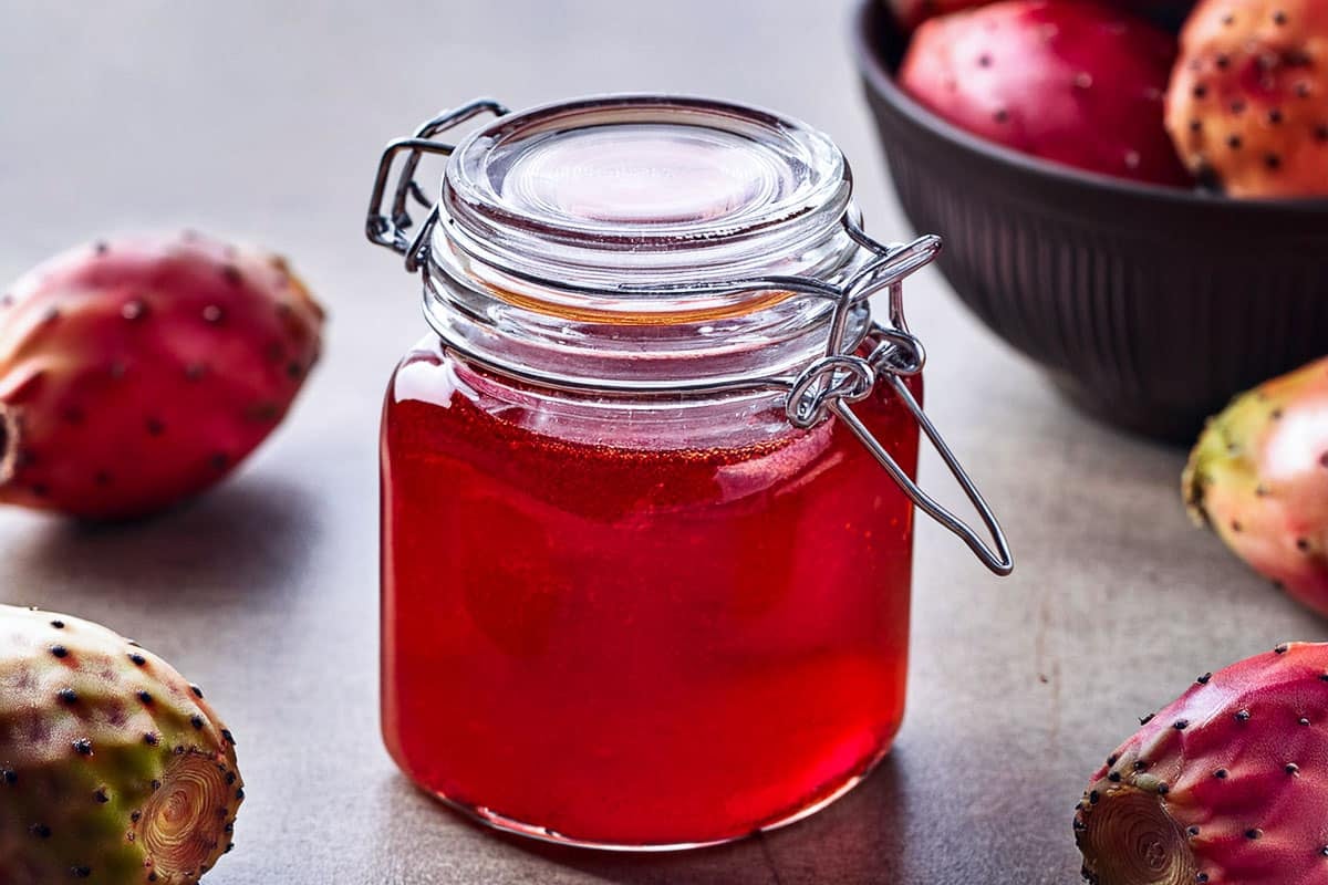 prickly pear syrup in a jar with prickly pears around it
