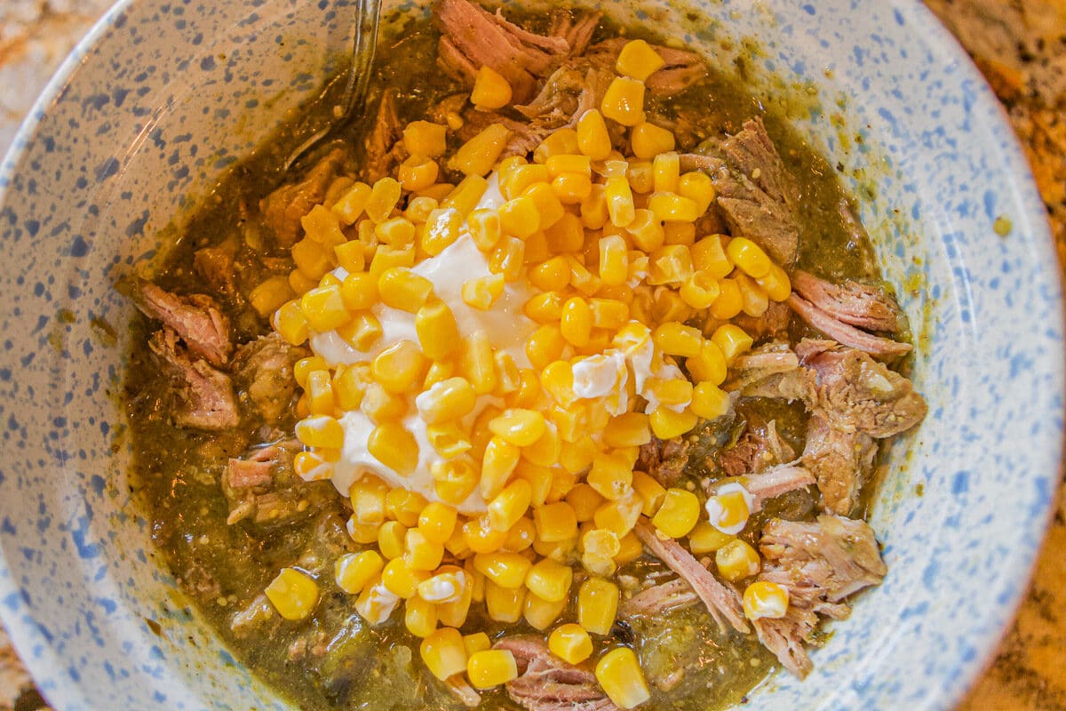 chili verde with corn and sour cream in a bowl