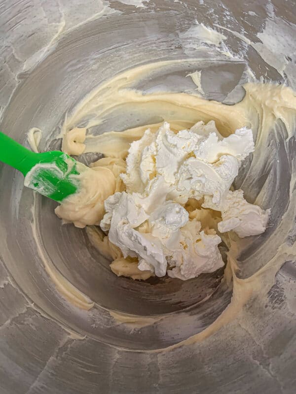 whip cream added to cream cheese filling in a  bowl