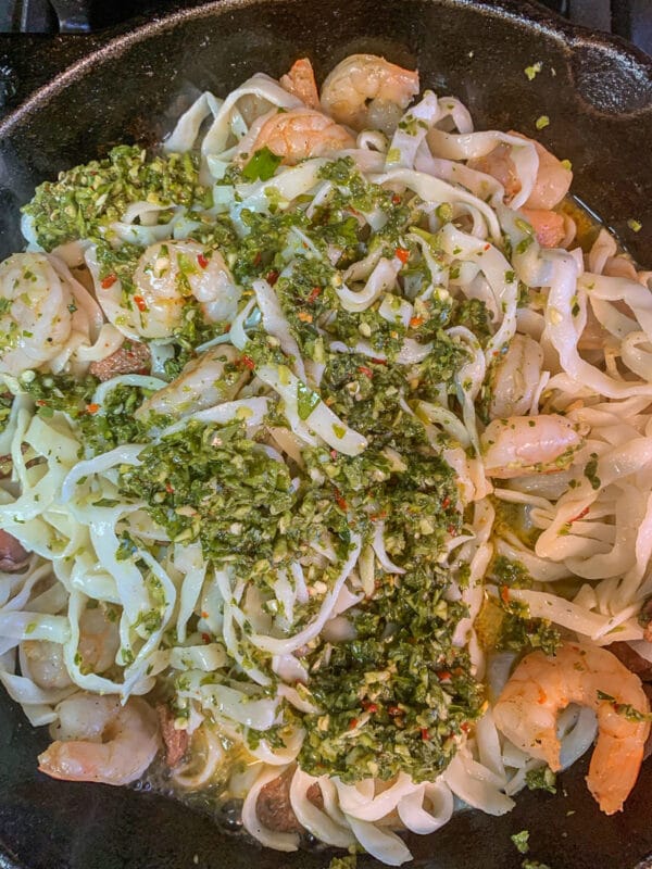 protein noodles in a pan with green herb sauce