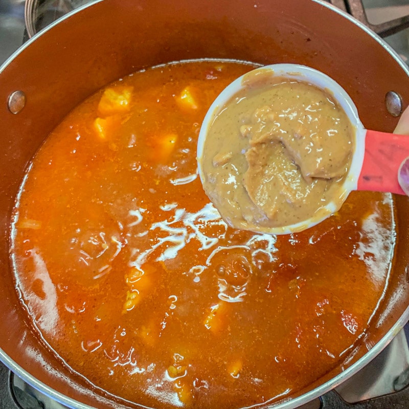 peanut butter being poured into stew