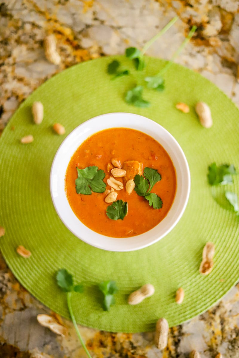 african peanut soup in a white bowl on a green placemat