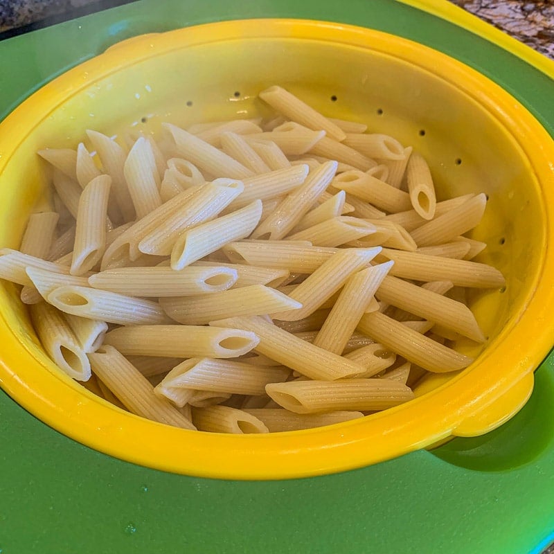 cooked pasta in  a yellow and green stainer