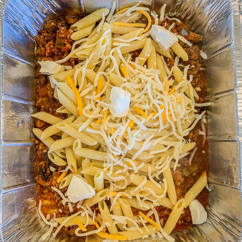 pasta with cheese and cubed cream cheese in a pan