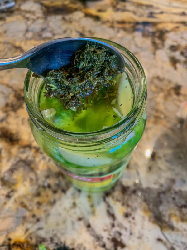 adding herbs to pickle jar