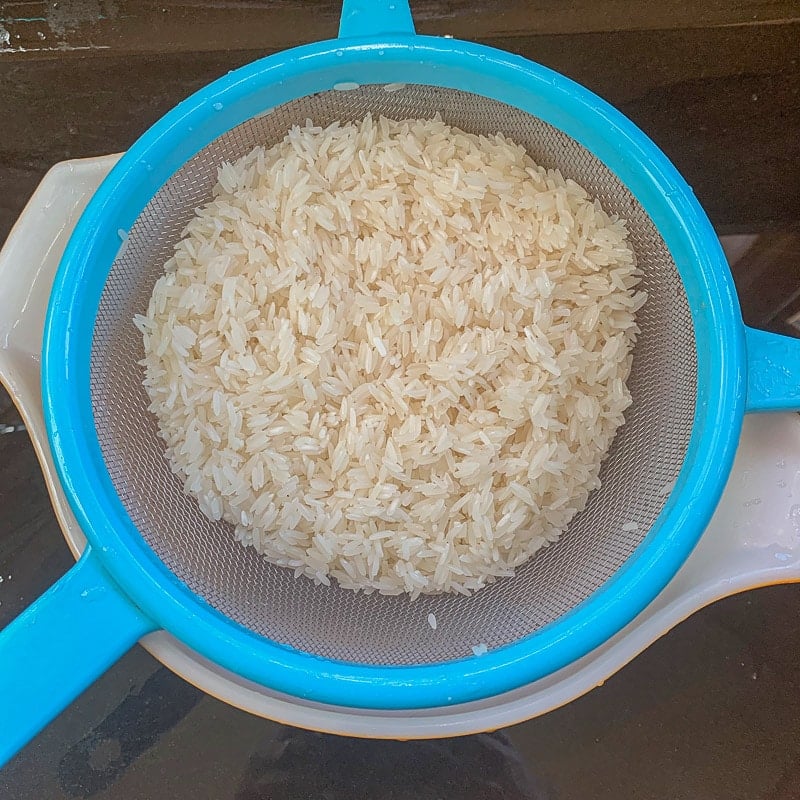 straining rice through a blue strainer