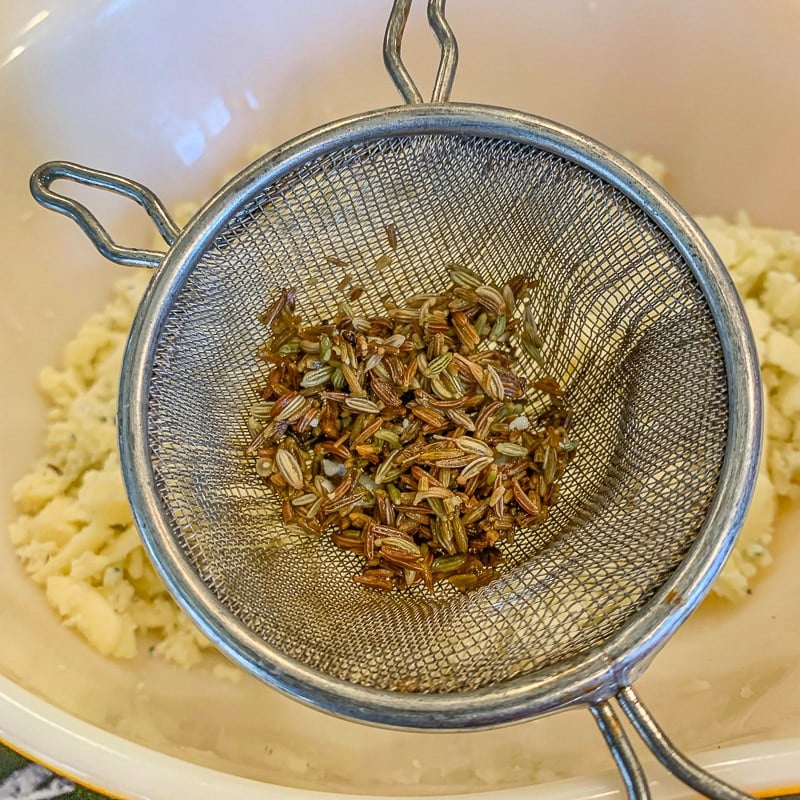 seeds in a strainer over a bowl of cheese