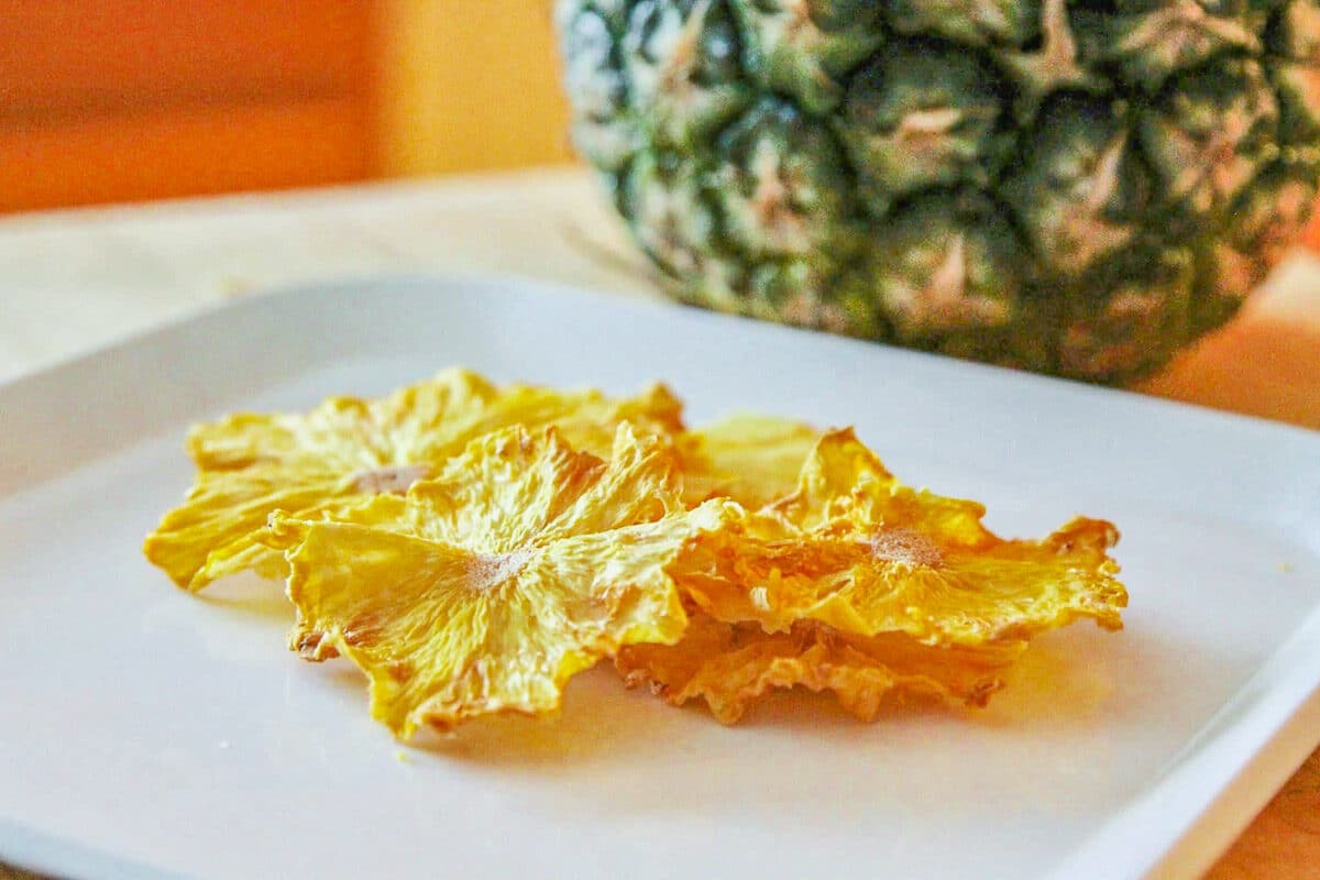 pineapple chips in a plate with a pineapple in the background