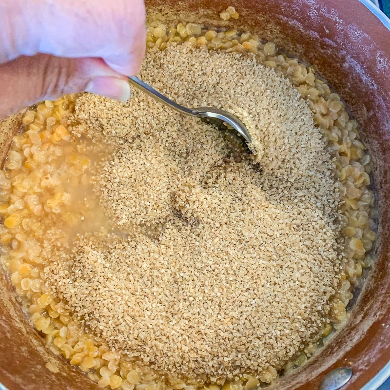 stirring lentil and bulgur in a pot