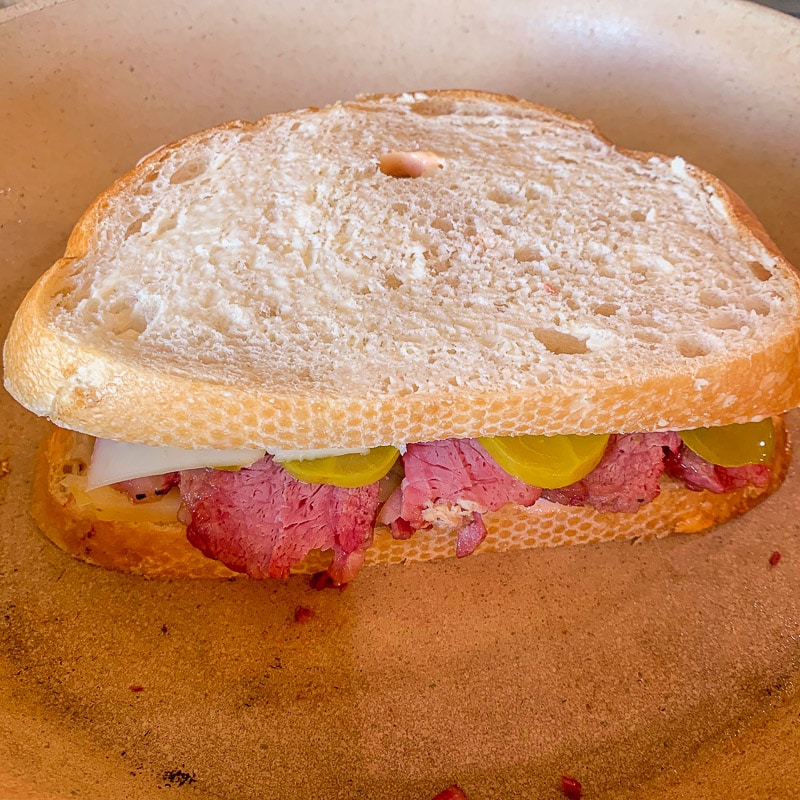 reuben sandwich being grilled in a pan