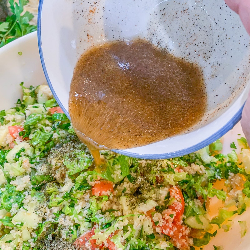 pouring dressing on Tabbouleh salad