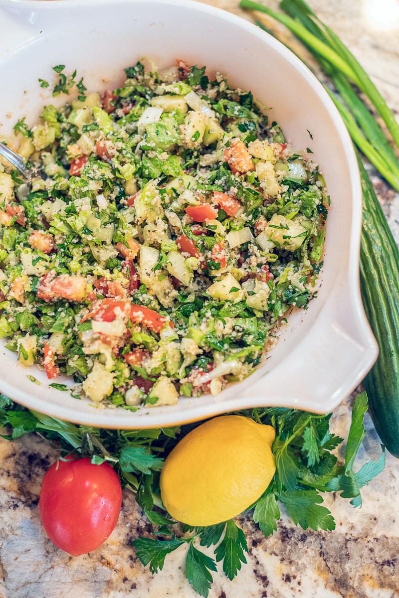 Tabouli salad in a bowl with veggies around it