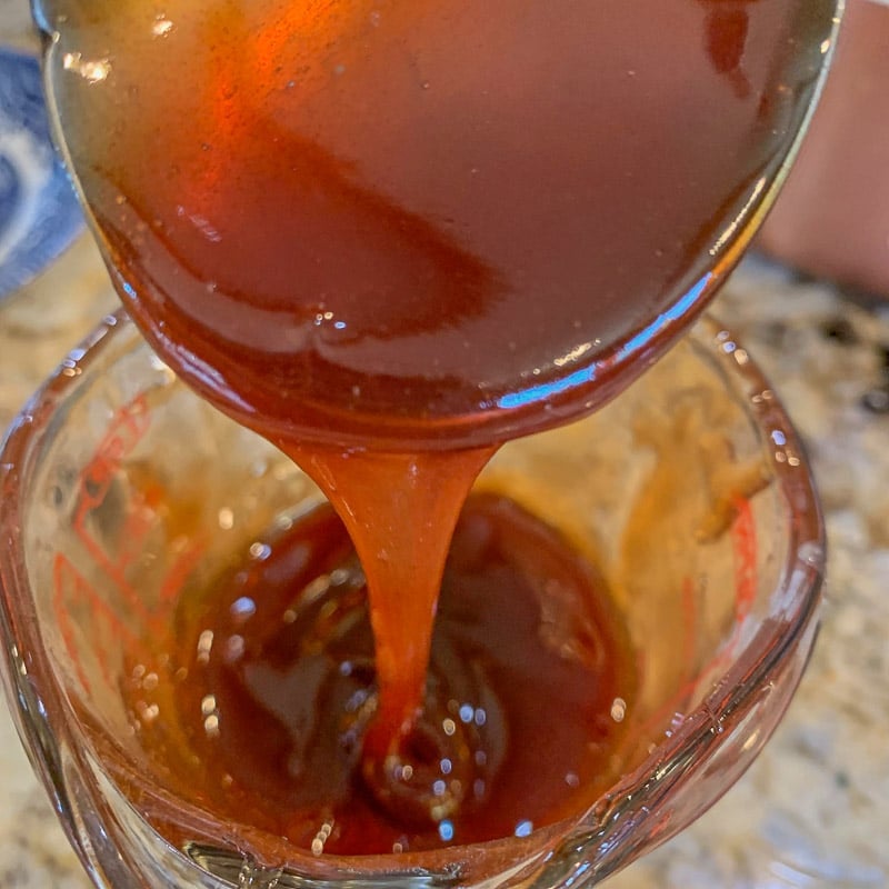 pouring date syrup into a measuring cup