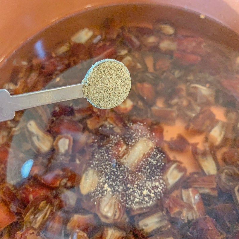 adding cardamom to dates in a pot