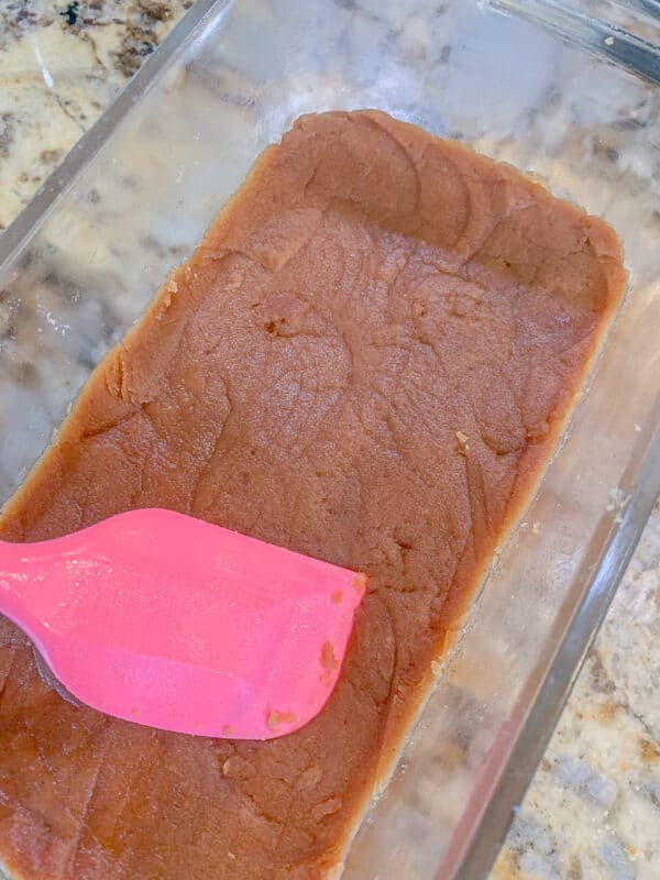 pressing halwa in a pan with a pink spatula