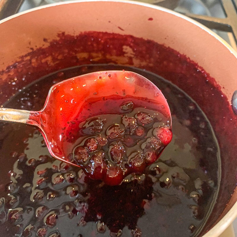 huckleberry sauce being spooned in a pot