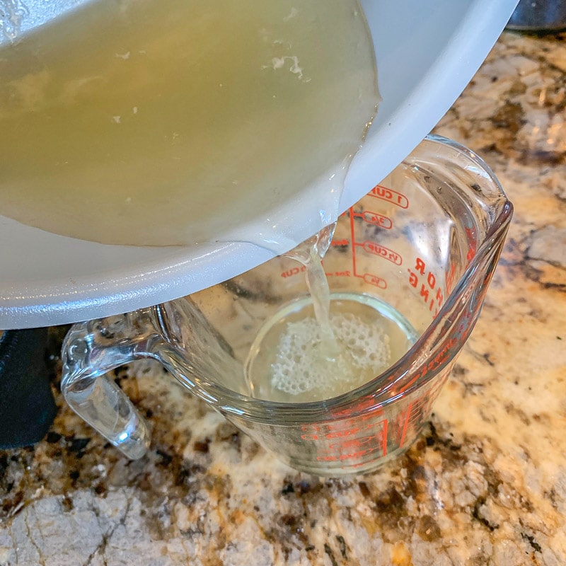 pouring broth into measuring cup