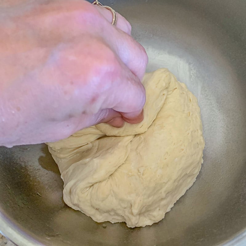 folding dough over in a bowl