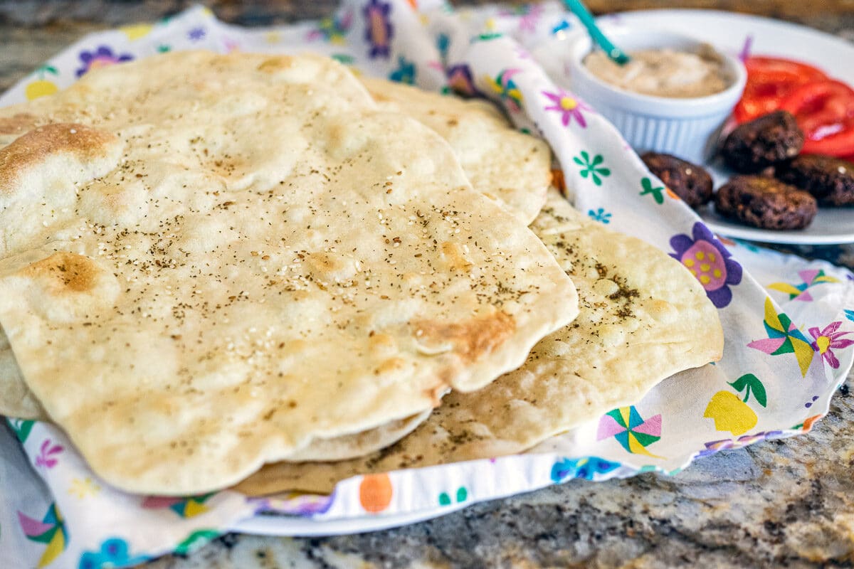 lavash bread on a flowered dish cloth with other fixings in the background