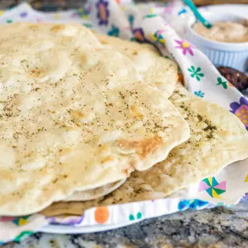 lavash bread on a flowered dish cloth with other fixings in the background