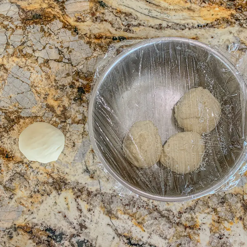 3 portions de pâte dans un bol et une sur le comptoir