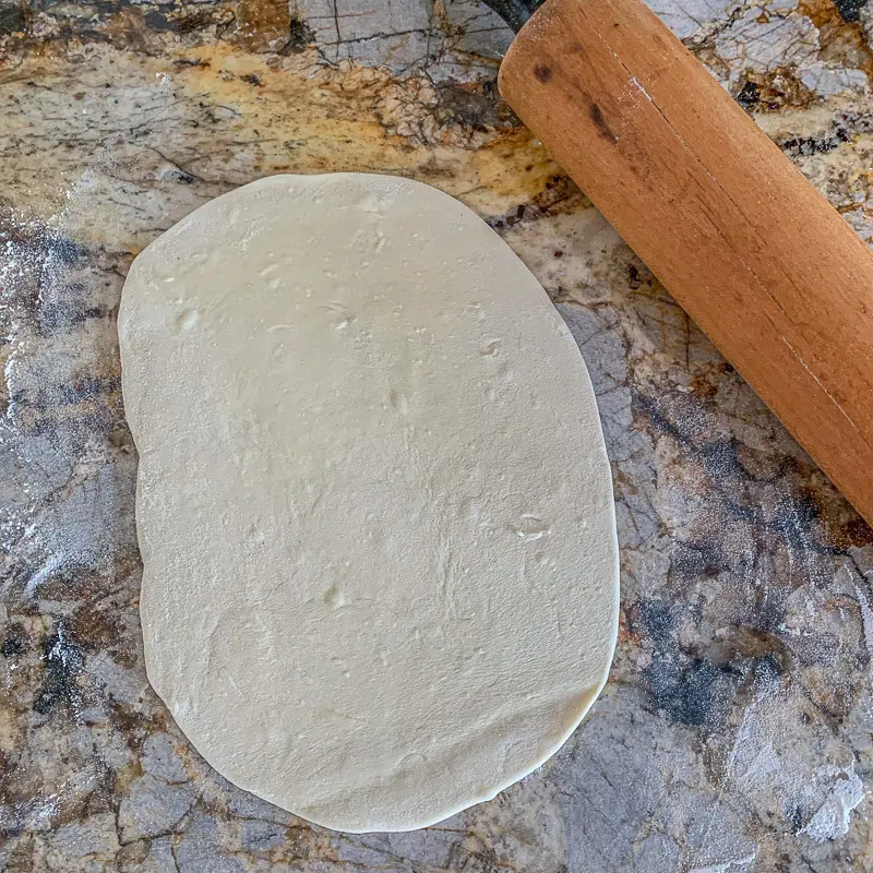 massa de pãolavash enrolada em balcão com um rolo de pasteleiro