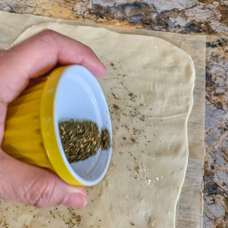 Sprenkeln von Zaatar auf Lavash-Brot