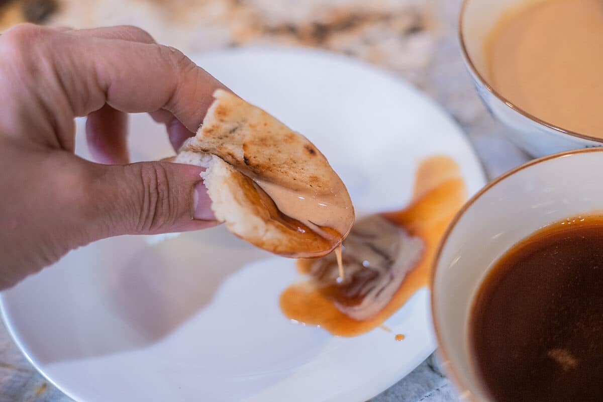 dipping pita bread into date syrup and tahini