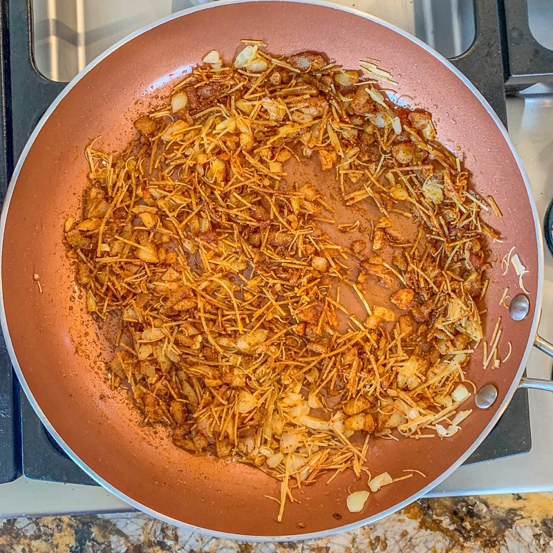 onions and noodles being sautéed in a pan