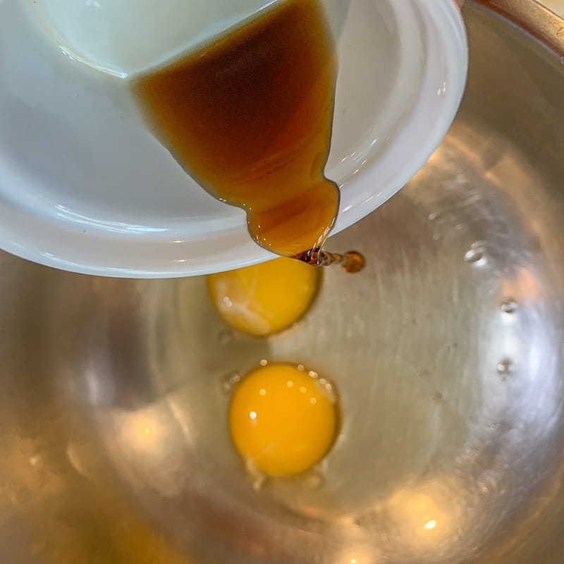 vanilla being added to eggs in a bowl
