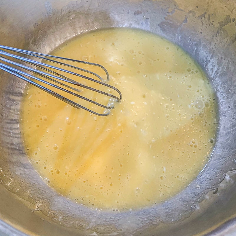 whisking wet ingredients for banana bread in a sliver bowl