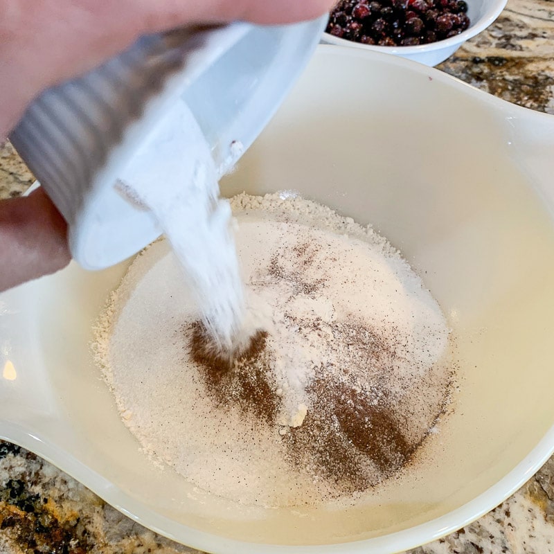 pouring spices into a white bowl with flour